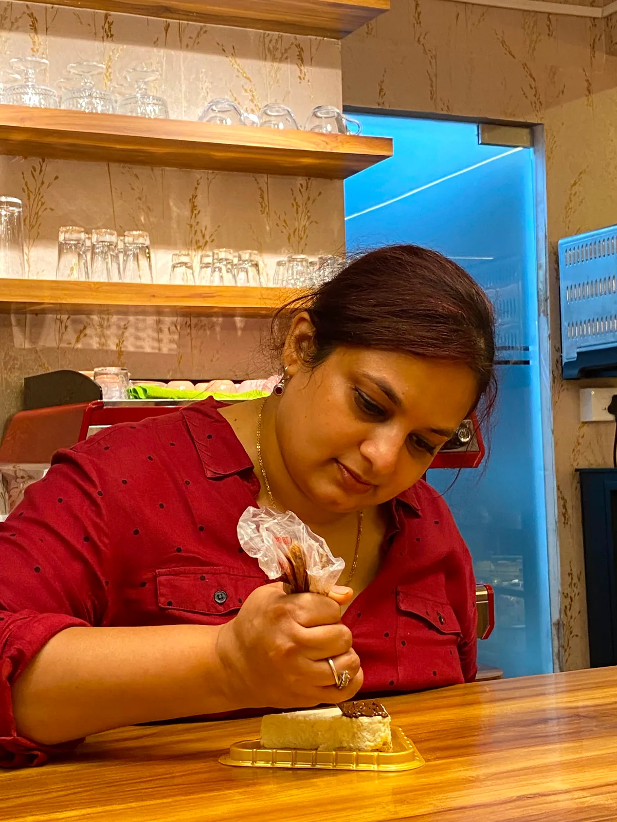 Pooja, who runs Tessori, piping decoration onto a dessert at the café counter