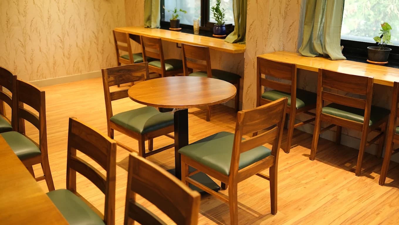 A round table and a long wooden counter with high-backed chairs along the windows at Tessori
